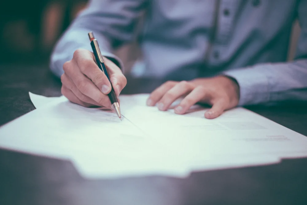 Firma de un documento sobre una mesa de despacho